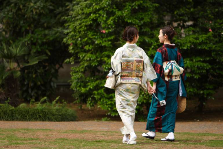 Two women in kimono go for a stroll and discuss ways to save money.
