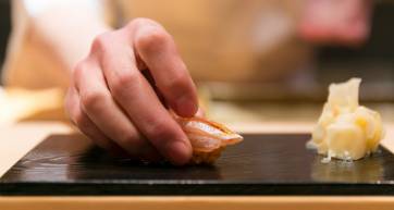 Sushi chef placing sushi on board
