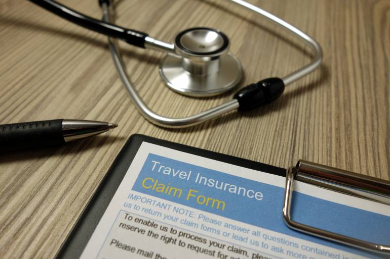 Travel insurance claim form with a pen and stethoscope