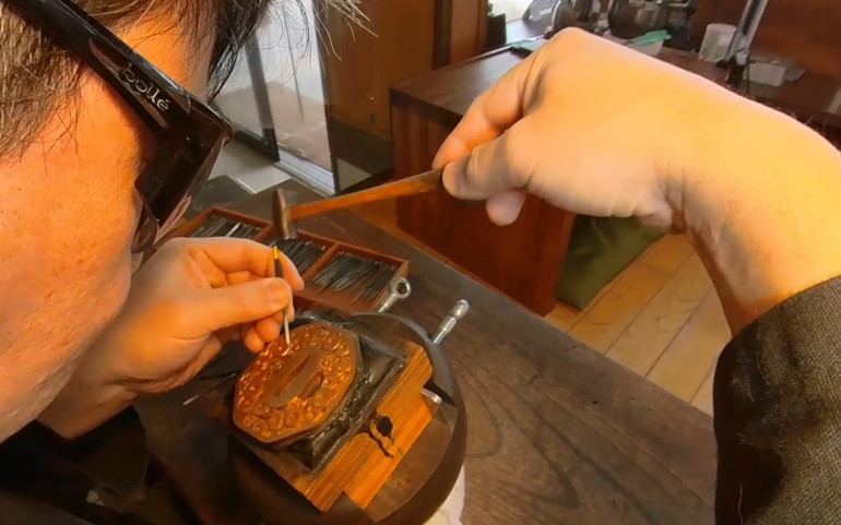 man with work goggles engraving a sword