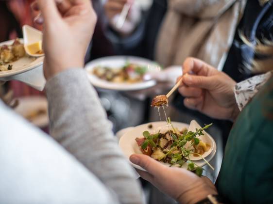 A group of people standing while they eat a tasty dish from a Fall food festival