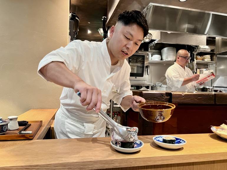 Chef searing a sushi roll at the counter of Rokkan, TOFROM YAESU TOWER