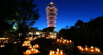 Candles glowing in the Samuel Cocking Garden beneath the lit-up Enoshima Sea Candle tower at dusk