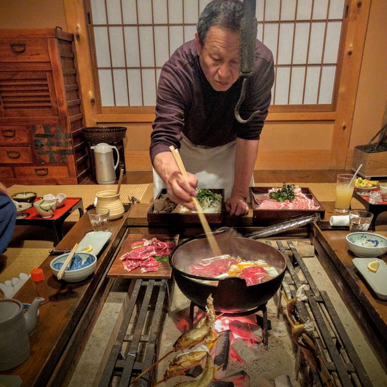 Takimi House owner cooking over the irori hearth