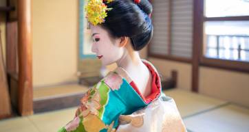 Maiko Apprentice Geisha sitting in Japanese tatami room, looking over shoulder