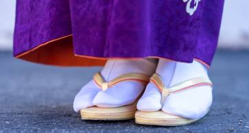 A closeup photograph of a woman in traditional Japanese kimono, zori sandals, and tabi socks.