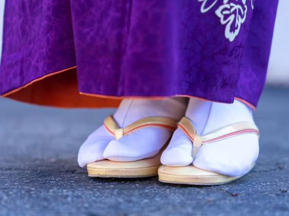 A closeup photograph of a woman in traditional Japanese kimono, zori sandals, and tabi socks.
