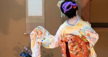 Back view of elderly Japanese woman, with hair ornament, in flower-patterned kimono, dancing Japanese traditional dance in Japanese room