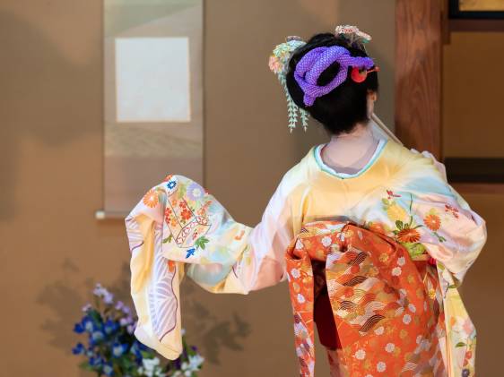 Back view of elderly Japanese woman, with hair ornament, in flower-patterned kimono, dancing Japanese traditional dance in Japanese room