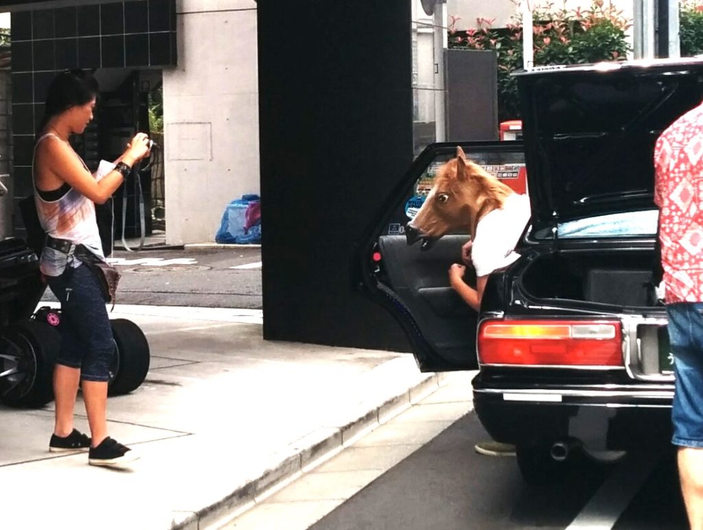 tokyo cheapo youtube production, woman filming man with fake horse head getting out of taxi